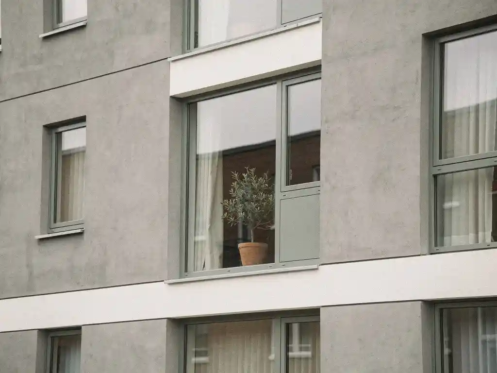 Nieuw appartementengebouw in Rijswijk zonder balkons, met moderne betonnen gevel en een kamerplant op de vensterbank.